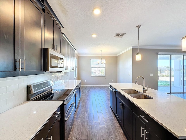 kitchen featuring appliances with stainless steel finishes, tasteful backsplash, a textured ceiling, sink, and pendant lighting