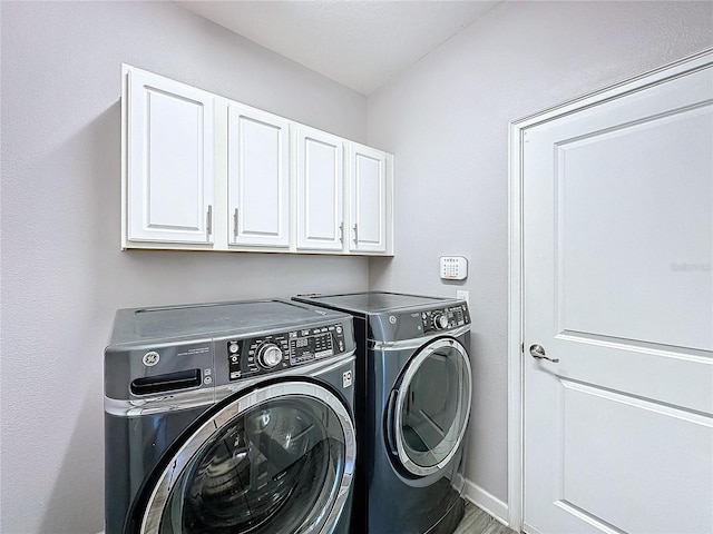 washroom with washer and dryer and cabinets