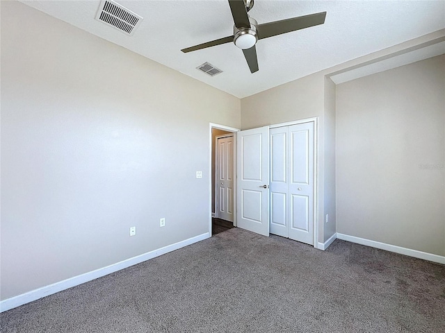 unfurnished bedroom featuring ceiling fan, a closet, and dark carpet