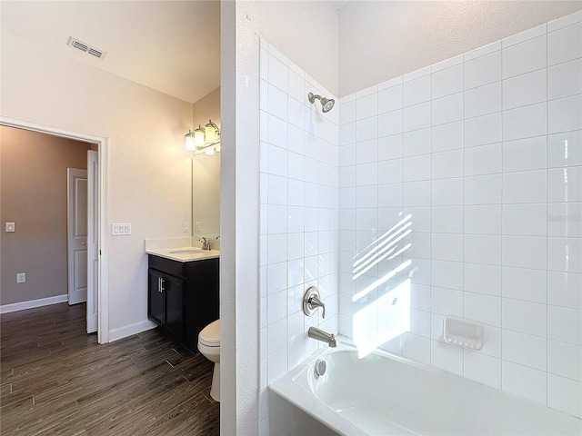 full bathroom with hardwood / wood-style flooring, tiled shower / bath combo, toilet, and vanity