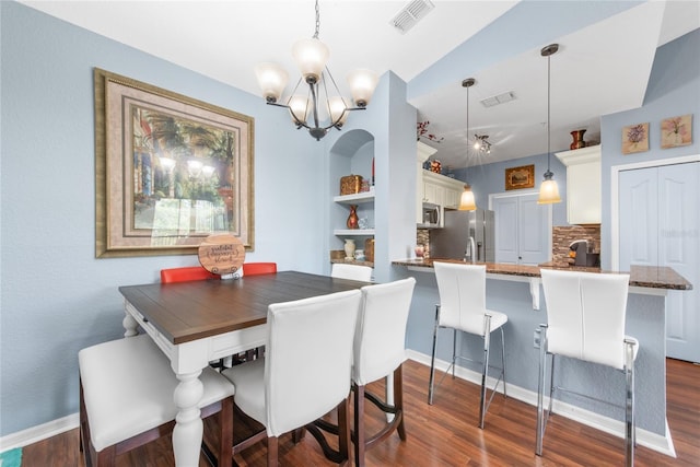 dining area featuring vaulted ceiling, dark hardwood / wood-style flooring, built in features, and an inviting chandelier