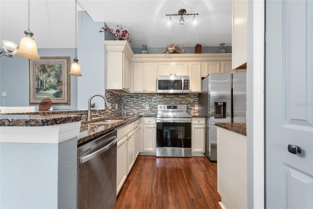 kitchen with sink, dark hardwood / wood-style flooring, backsplash, decorative light fixtures, and appliances with stainless steel finishes