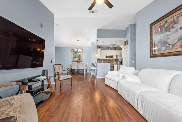 living room with ceiling fan with notable chandelier and dark wood-type flooring