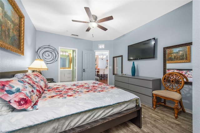 bedroom with ensuite bathroom, wood-type flooring, and ceiling fan with notable chandelier