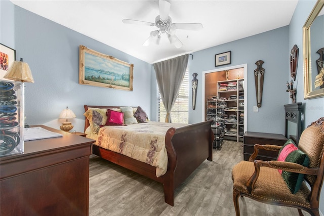 bedroom with a walk in closet, light wood-type flooring, and ceiling fan