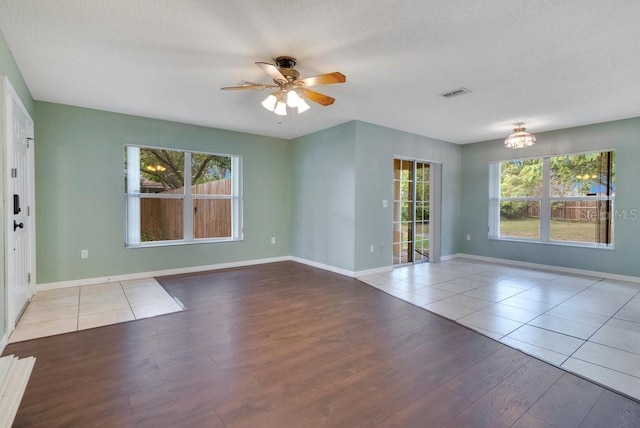 interior space featuring hardwood / wood-style floors, ceiling fan with notable chandelier, and a textured ceiling