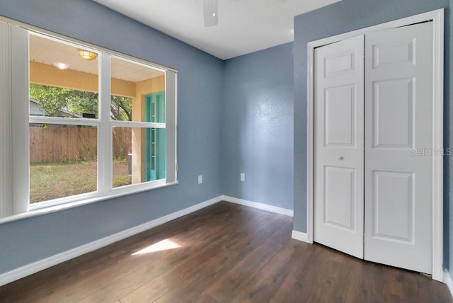 unfurnished bedroom with ceiling fan, a closet, and dark wood-type flooring