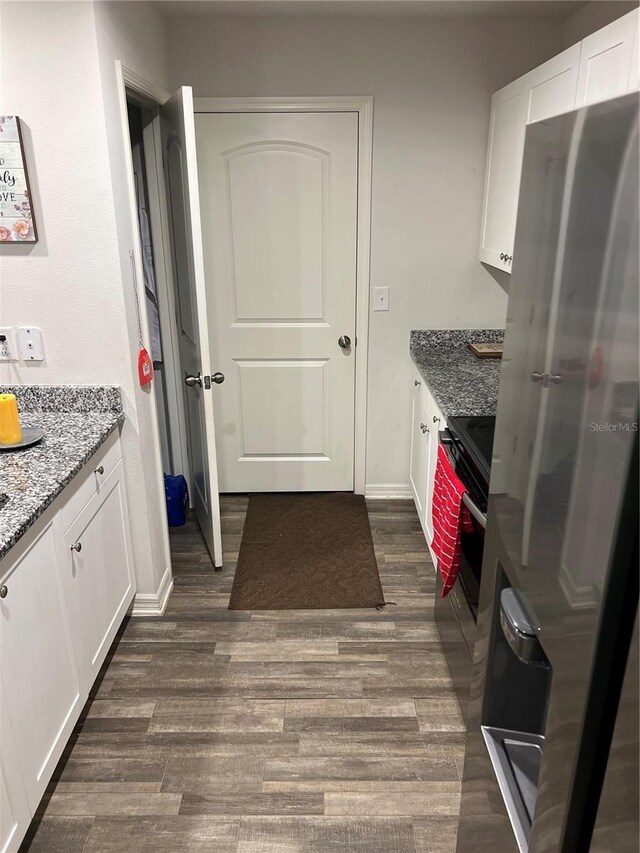 kitchen with white cabinets, dark hardwood / wood-style flooring, appliances with stainless steel finishes, and dark stone counters