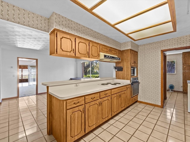 kitchen featuring oven, kitchen peninsula, white cooktop, and a wealth of natural light