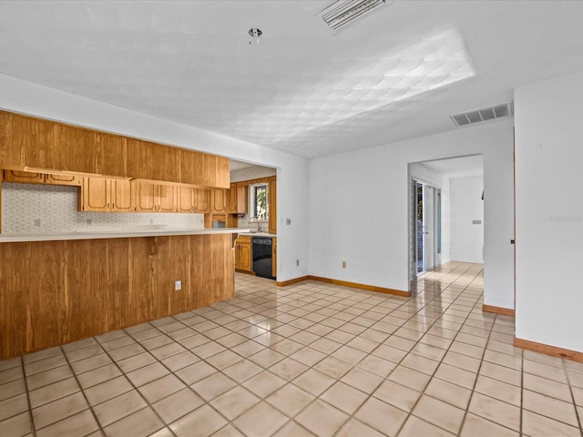 kitchen featuring kitchen peninsula, light tile patterned floors, black dishwasher, and backsplash