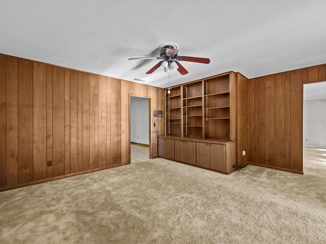 unfurnished living room featuring light carpet, ceiling fan, and wooden walls