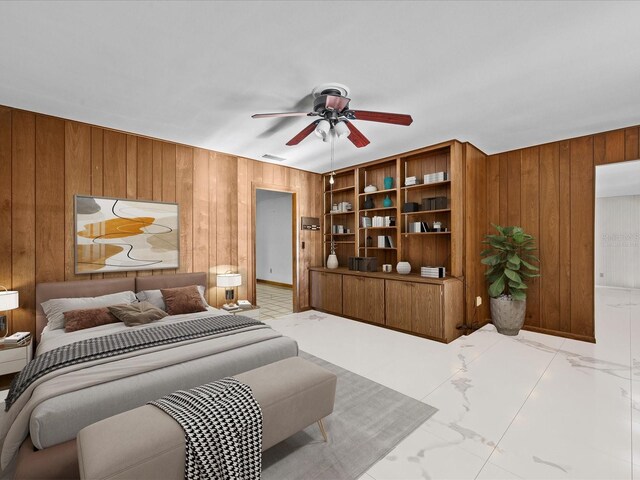 bedroom featuring ceiling fan and wooden walls