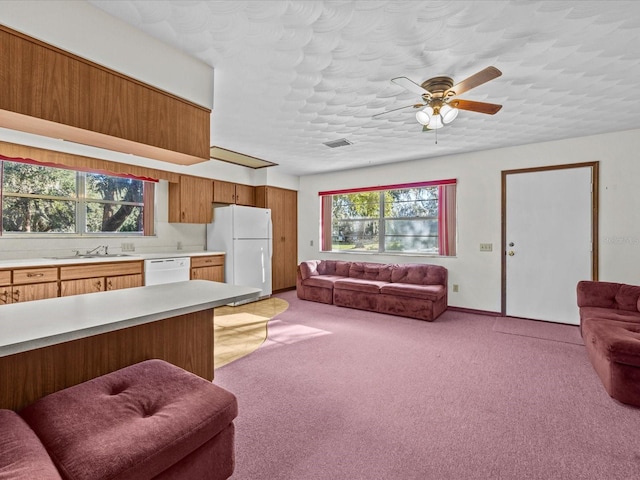 living room with ceiling fan, sink, light colored carpet, and a textured ceiling