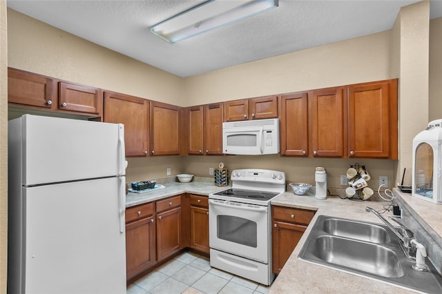 kitchen with a textured ceiling, sink, light tile patterned floors, and white appliances