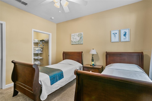 bedroom with ceiling fan, light colored carpet, a walk in closet, and a closet