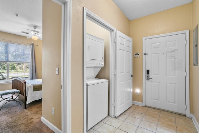 laundry room with light tile patterned floors, ceiling fan, and stacked washer / drying machine