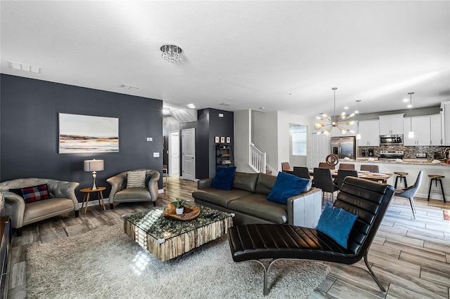 living room featuring a chandelier, a textured ceiling, and light wood-type flooring