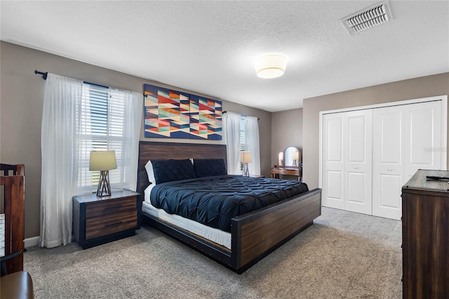 bedroom with light colored carpet, a textured ceiling, and a closet