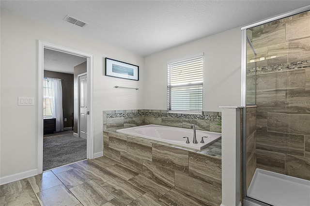 bathroom featuring a healthy amount of sunlight, a textured ceiling, and shower with separate bathtub