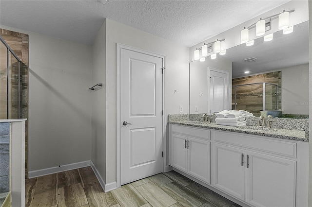 bathroom with hardwood / wood-style floors, vanity, an enclosed shower, and a textured ceiling