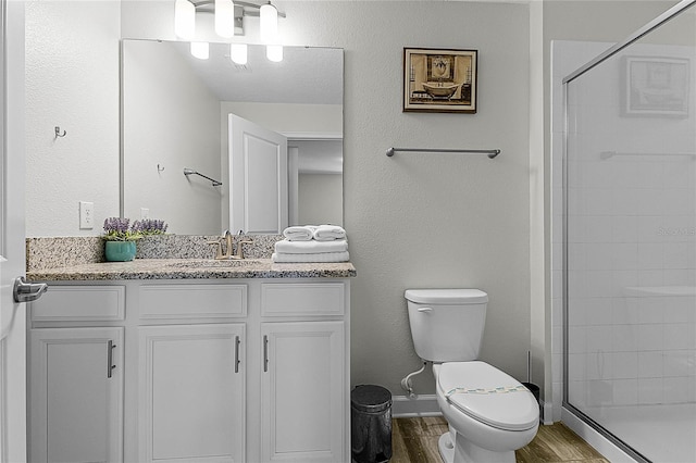 bathroom featuring hardwood / wood-style flooring, vanity, toilet, and walk in shower