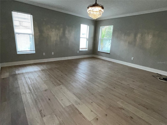 empty room featuring a chandelier, hardwood / wood-style floors, and ornamental molding