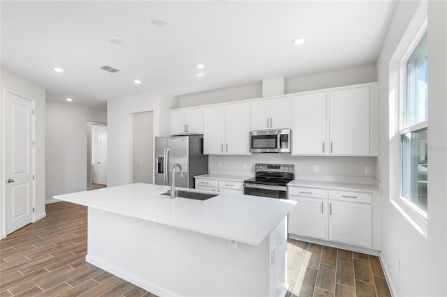 kitchen featuring a sink, a kitchen island with sink, stainless steel appliances, and light countertops