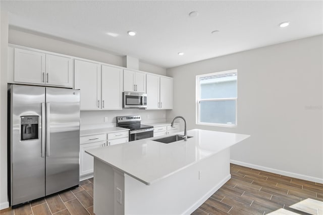 kitchen with white cabinets, a kitchen island with sink, stainless steel appliances, and a sink