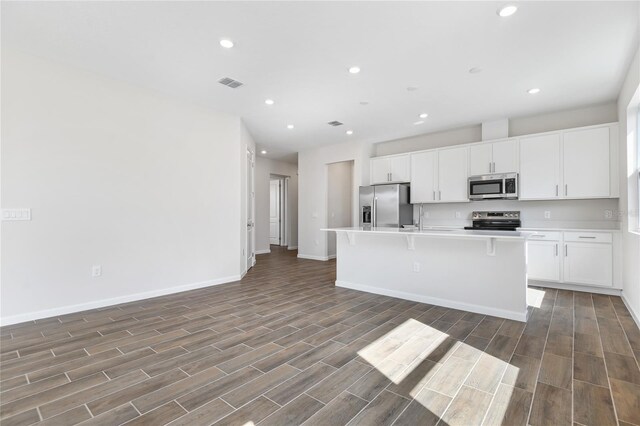 kitchen featuring a kitchen island with sink, stainless steel appliances, a breakfast bar, visible vents, and light countertops