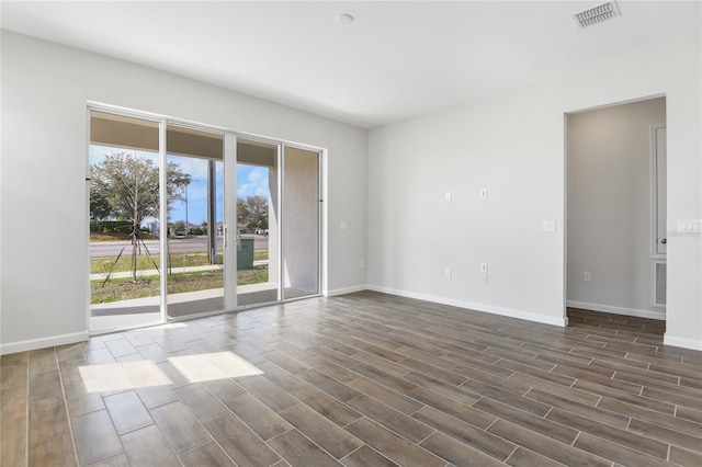 unfurnished room with dark wood-style flooring, visible vents, and baseboards