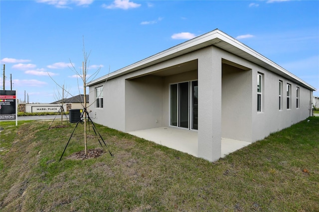 back of property with central air condition unit, a lawn, and stucco siding