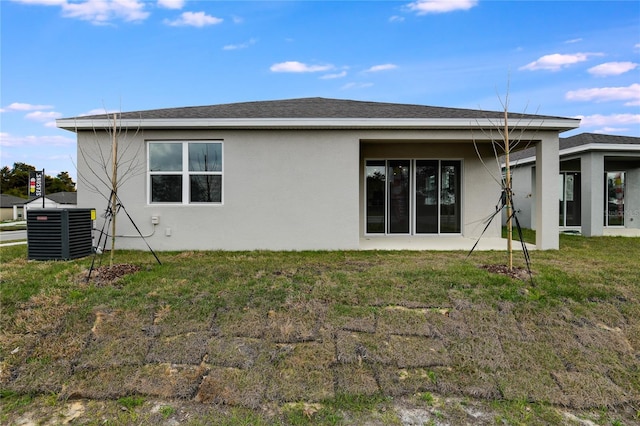 rear view of house with a yard, roof with shingles, cooling unit, and stucco siding