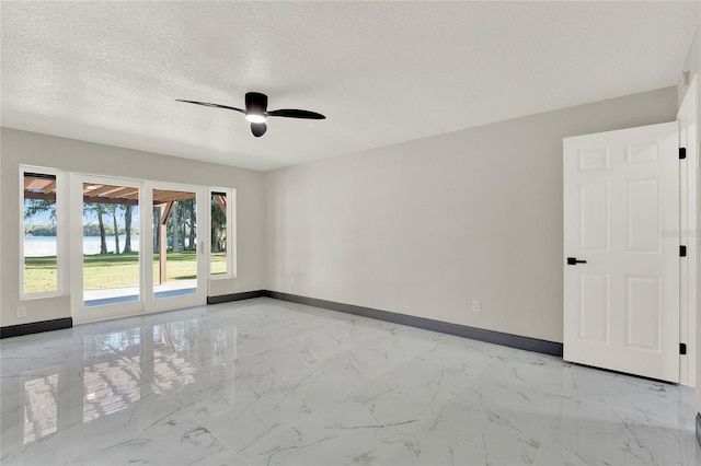 unfurnished room with ceiling fan and a textured ceiling