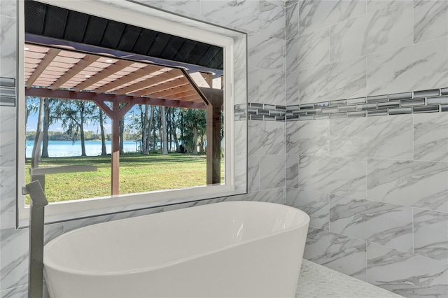 bathroom with a water view, tile walls, and a tub