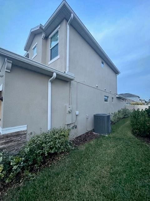 view of side of property featuring central AC unit and a lawn