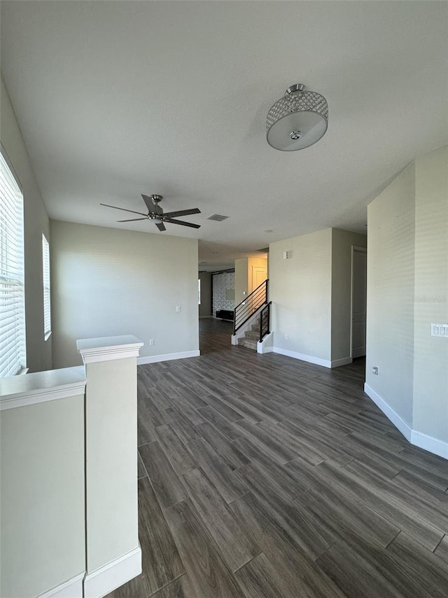 unfurnished living room with ceiling fan and dark wood-type flooring