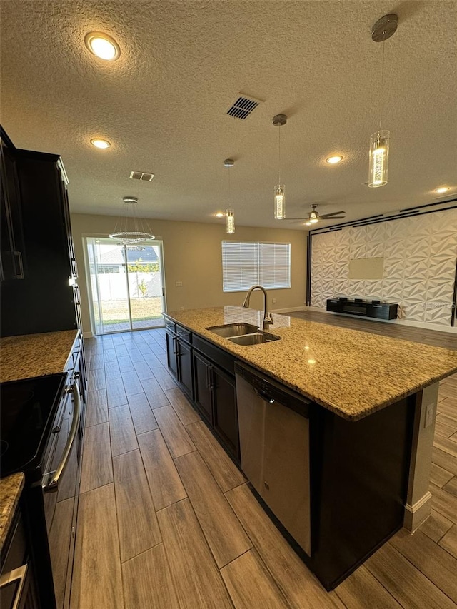 kitchen with a center island with sink, sink, a textured ceiling, and appliances with stainless steel finishes