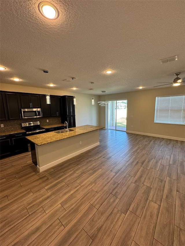 kitchen featuring light stone countertops, sink, light wood-type flooring, and appliances with stainless steel finishes