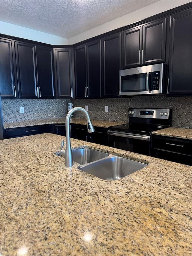 kitchen featuring a textured ceiling, sink, stainless steel appliances, and tasteful backsplash