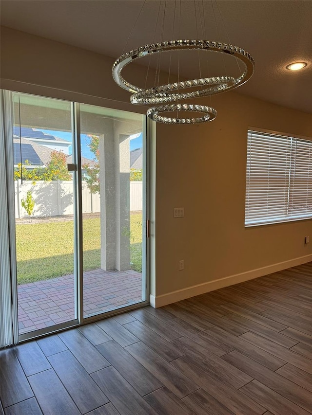 unfurnished dining area featuring a chandelier and wood-type flooring