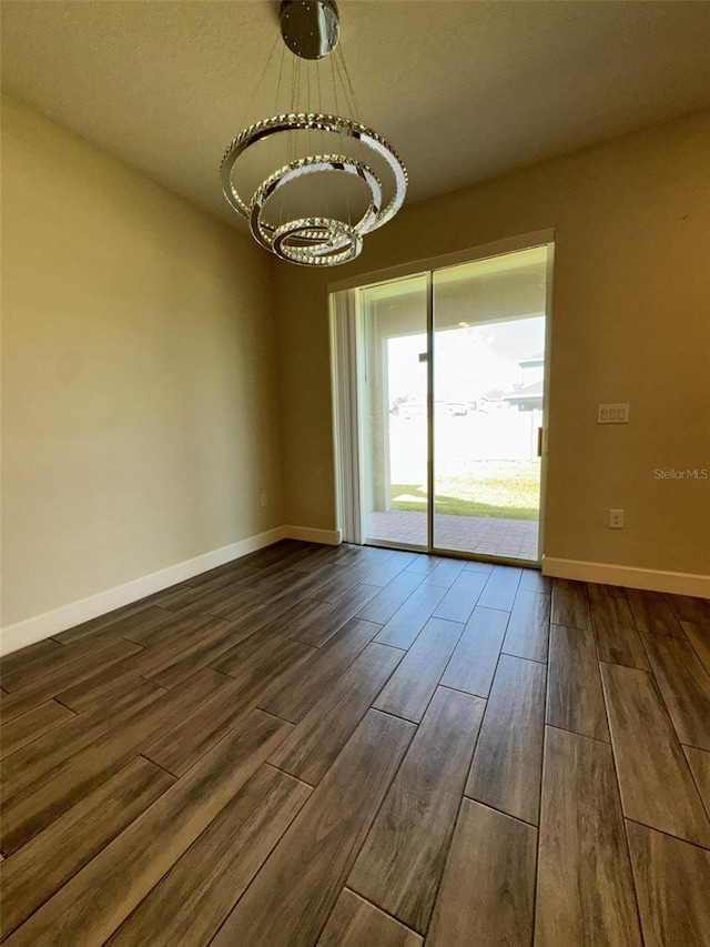 empty room featuring a chandelier, a textured ceiling, and dark hardwood / wood-style flooring