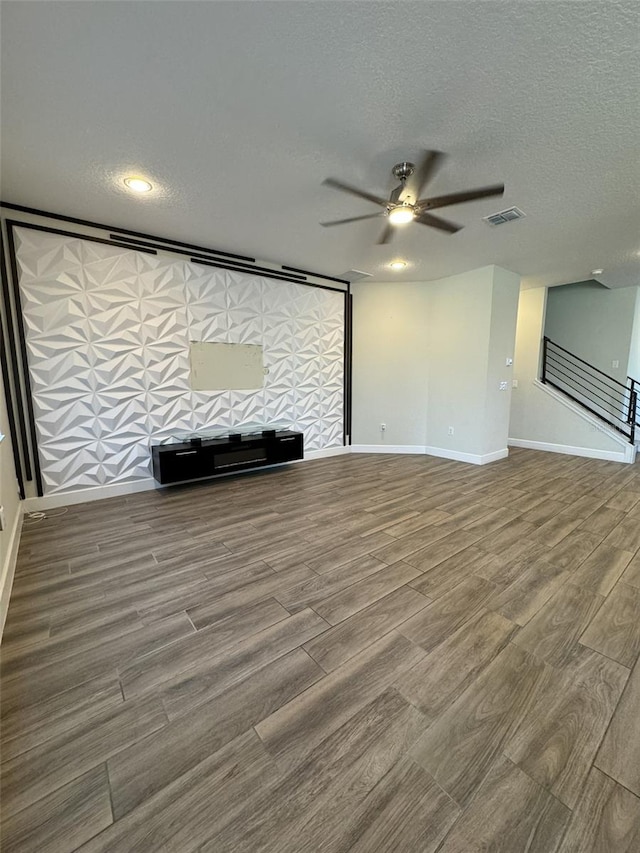 unfurnished living room with hardwood / wood-style floors, a textured ceiling, and ceiling fan