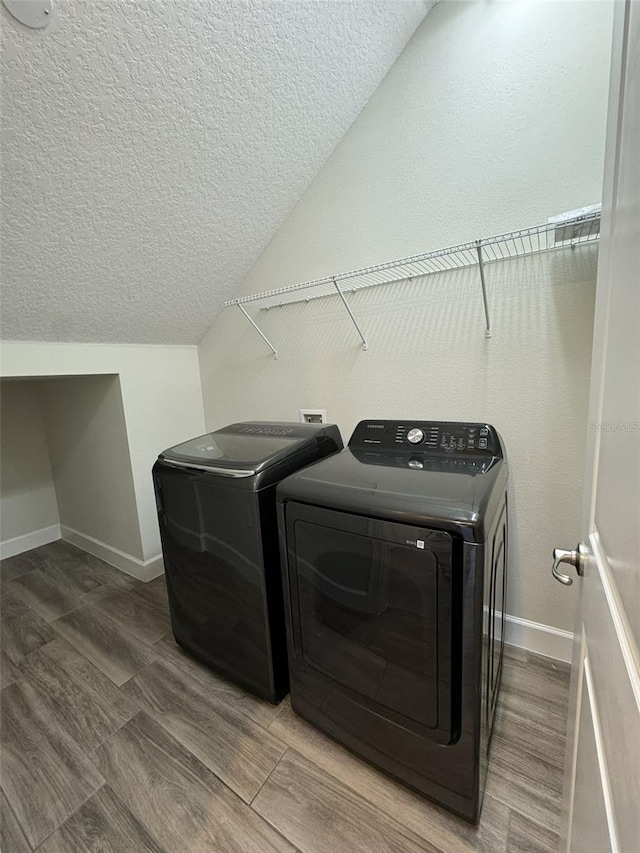 laundry room with wood-type flooring, a textured ceiling, and independent washer and dryer