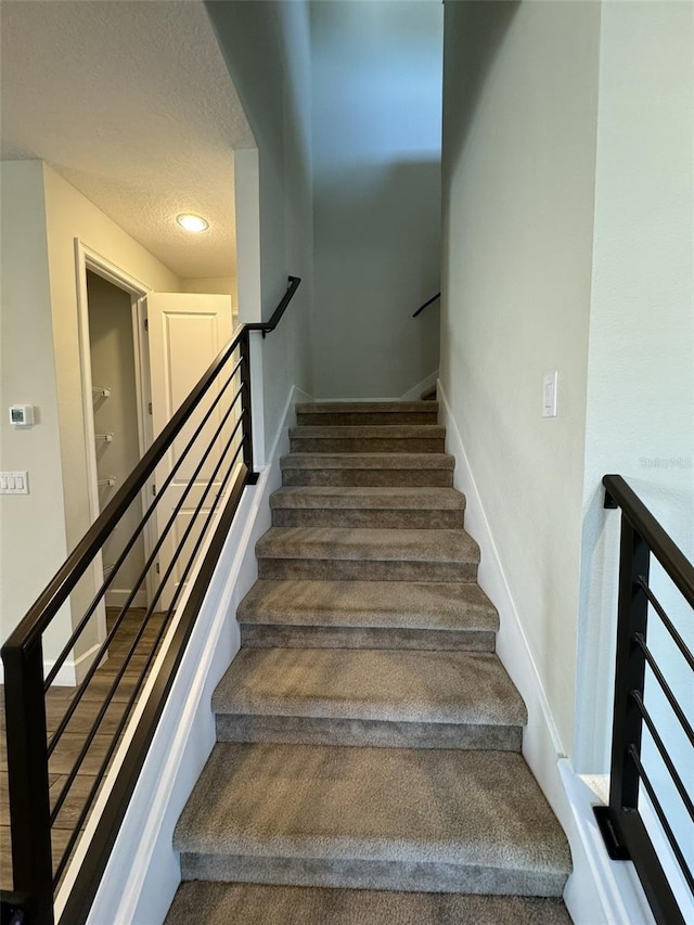 stairs with a textured ceiling