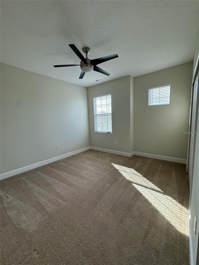 carpeted spare room featuring ceiling fan and a textured ceiling