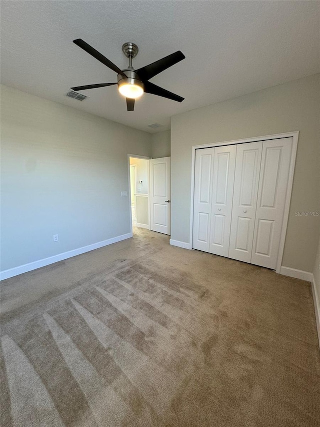 unfurnished bedroom featuring ceiling fan, carpet floors, a textured ceiling, and a closet