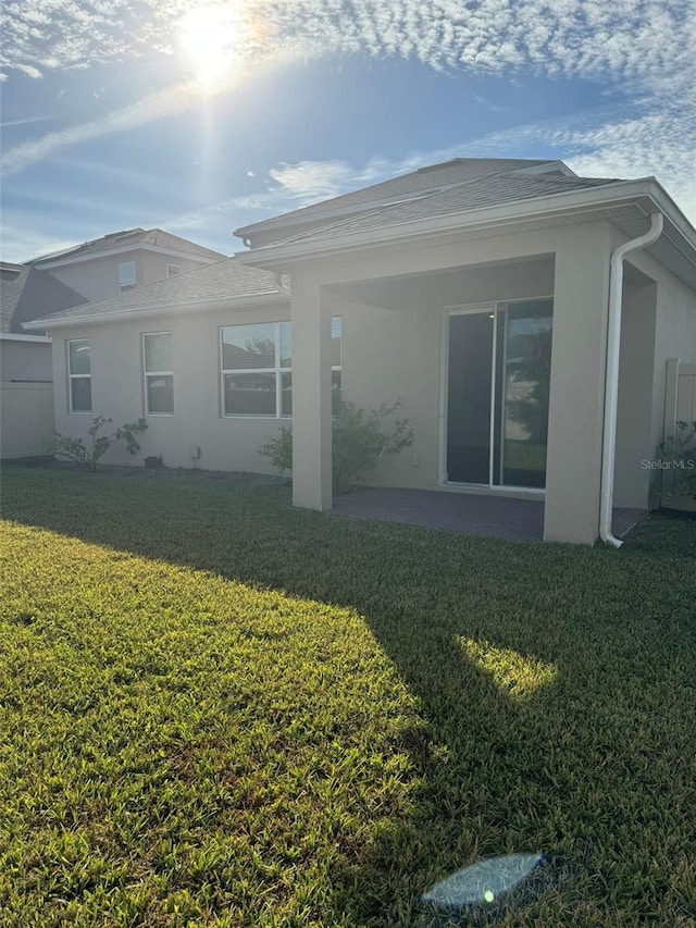 back of property with a patio area and a lawn