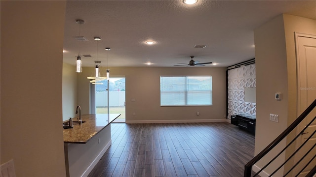 interior space featuring visible vents, a sink, dark wood finished floors, baseboards, and ceiling fan