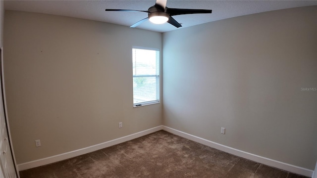 spare room with dark carpet, a textured ceiling, baseboards, and ceiling fan