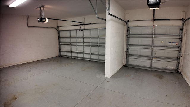 garage featuring concrete block wall and a garage door opener